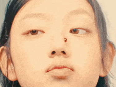 a close up of a girl 's face with a bug in her nose