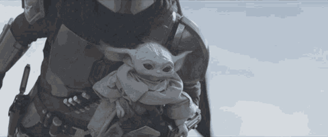 a man is carrying a baby yoda in his arms