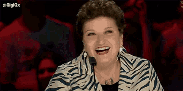 a woman in a zebra print jacket is smiling in front of a crowd .