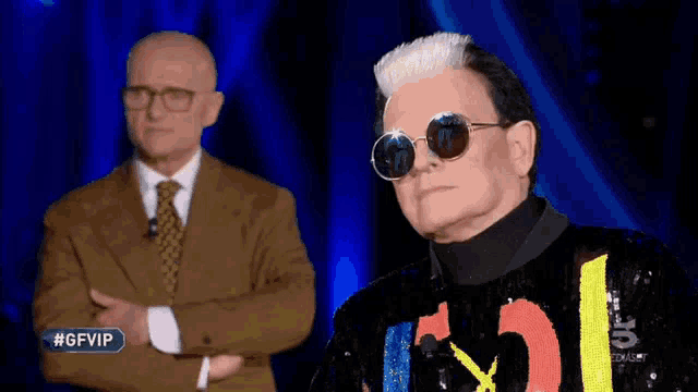 a man in a suit and tie stands next to a man wearing sunglasses and a jacket that says #gfvip