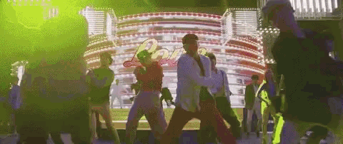 a group of people are dancing on a stage in front of a sign that says ' paris ' .