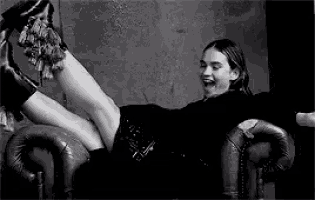 a woman is sitting on a couch with her legs up and laughing .