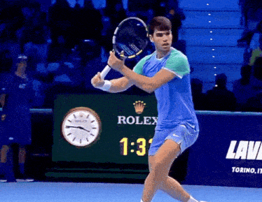 a tennis player is swinging his racket in front of a rolex sign