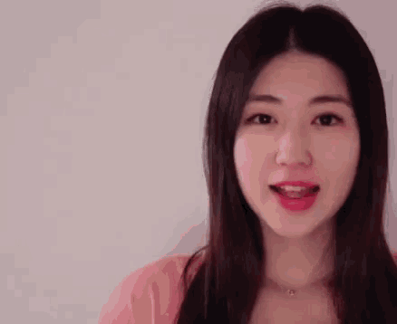 a close up of a woman 's face with her mouth open and a pink shirt on .