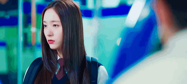 a girl in a school uniform and tie is looking at a man in a blue shirt .
