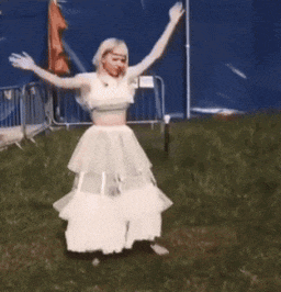 a woman in a white dress is dancing in the grass .