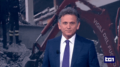 a man in a suit and tie is standing in front of a red machine that says vigili del fuoco
