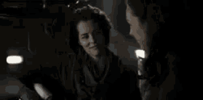 two women are standing next to each other in a dark room and smiling .