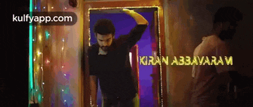 a man in a black shirt is standing in front of a sign that says kiran abbavaram