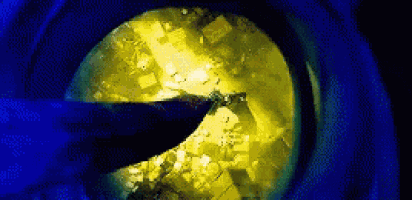 a close up of a person 's hand holding a knife in front of a yellow sphere .