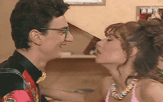 a man and a woman are looking into each other 's eyes in front of a sign that says abc