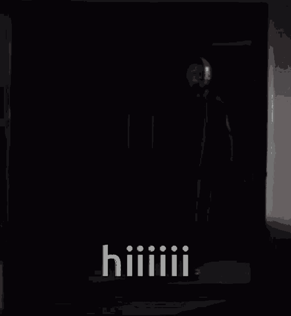 a man in a mask is standing in a dark room with the words hiiiiii written on the bottom .