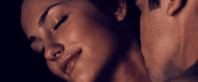 a close up of a man kissing a woman 's neck with her eyes closed