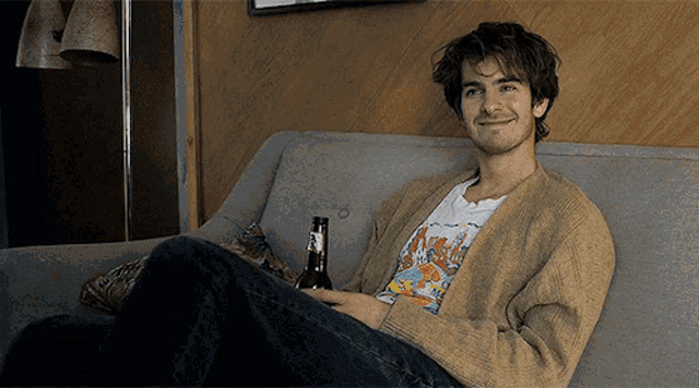 a man is sitting on a couch with a bottle of beer in his hand