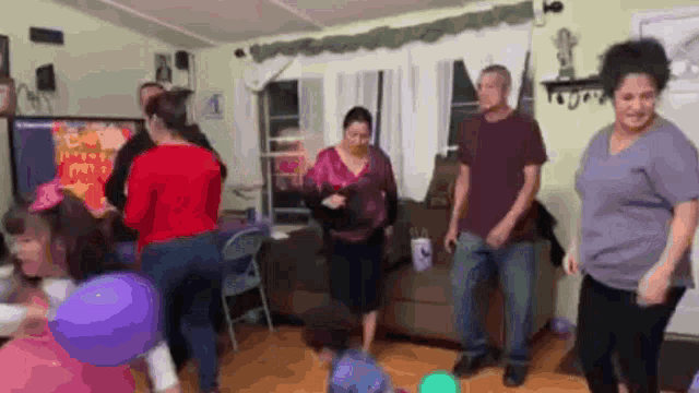 a group of people are dancing in a living room at a party .