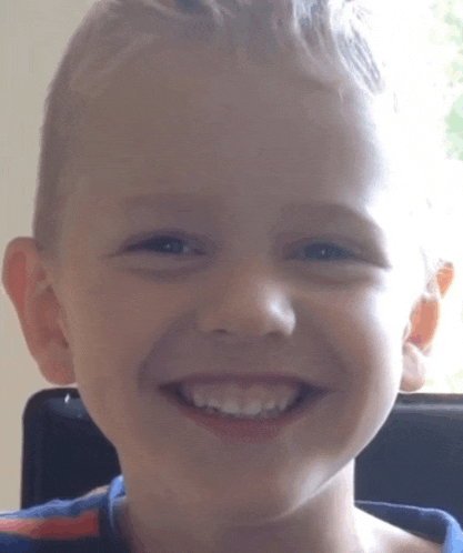 a close up of a young boy 's face smiling for the camera