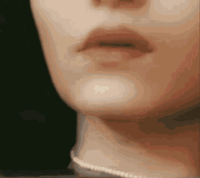 a close up of a woman 's lips with a pearl necklace around her neck .