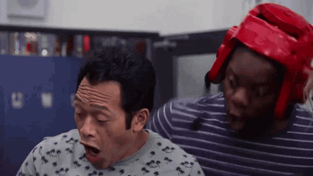 a man wearing a boxing helmet is standing next to another man with his mouth open