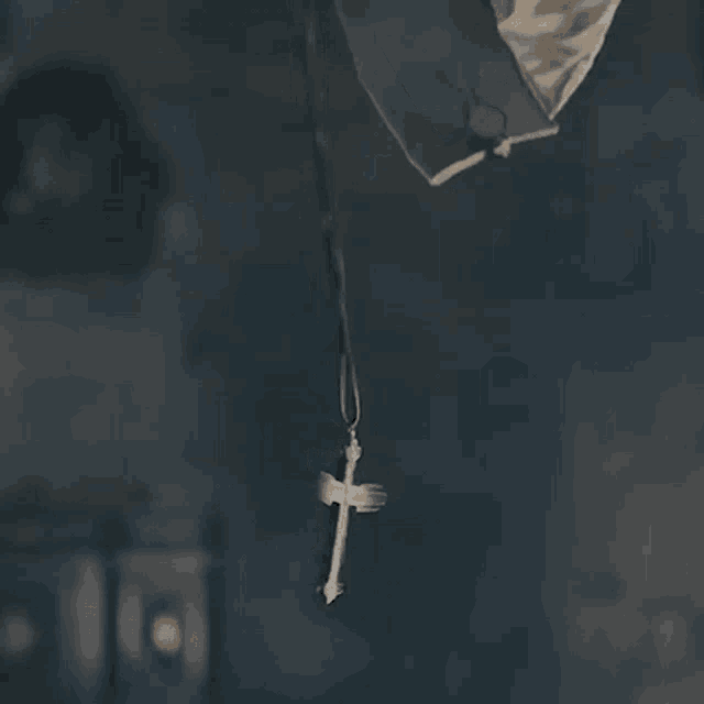 a close up of a cross hanging from a rope