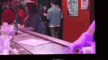 a group of people are standing around a bar talking to each other