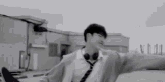 a young man wearing headphones and a tie is standing on a rooftop .