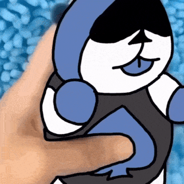 a person is holding a blue and white cartoon character with their tongue out .