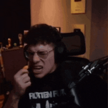 a man wearing glasses and headphones is sitting in front of a microphone and making a funny face .
