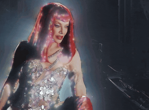 a woman with red hair is wearing a silver dress with sequins