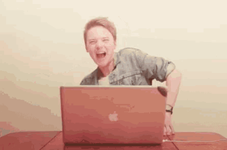 a man is laughing while using an apple laptop