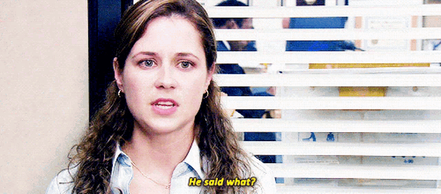 a woman is standing in front of a window with blinds and says he said what