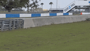 a race car is going down a track with a fence in the foreground