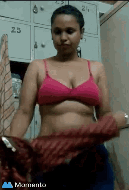 a woman in a pink bra is standing in front of lockers numbered 25 24 and 27