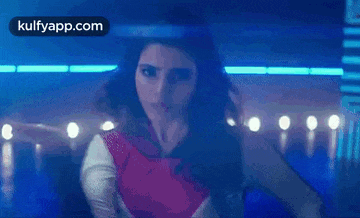 a woman is dancing in a dark room in front of a blue light .