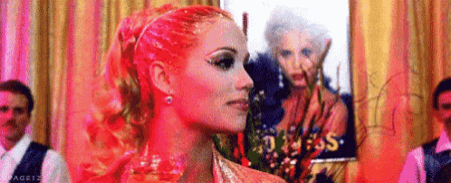 a woman with red hair and a ponytail is standing in front of a painting of a woman .