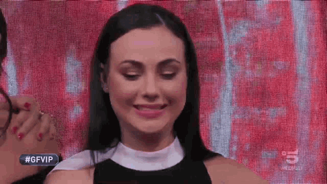 a woman is smiling in front of a screen that has the number 5 on it