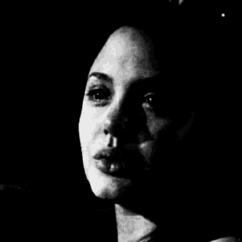 a black and white photo of a woman 's face with a shadow on her face .