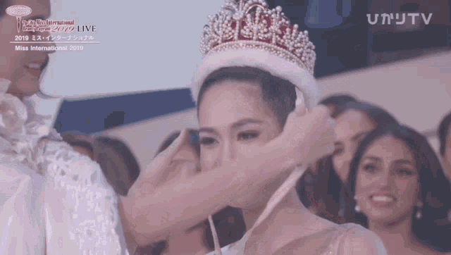 a woman wearing a crown is being interviewed by a tv channel