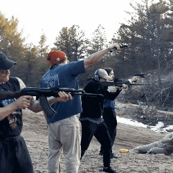 a man in a blue shirt that says ' freedom ' on the back is holding a gun