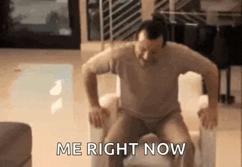 a man is sitting on a chair with his legs crossed and the words `` me right now '' written on the screen .