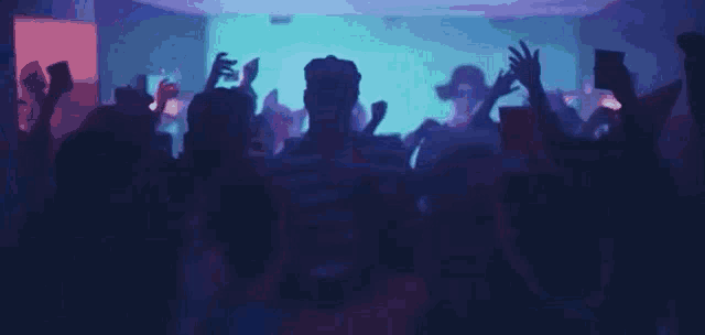a man in a striped shirt is dancing in a crowd of people at a party .