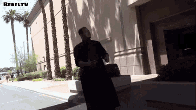 a man in a black robe is standing in front of a building with rebeltv written on the bottom
