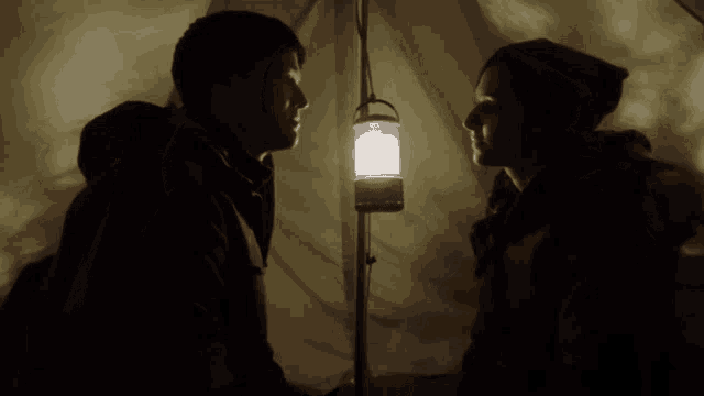 a man and woman looking at each other in a tent