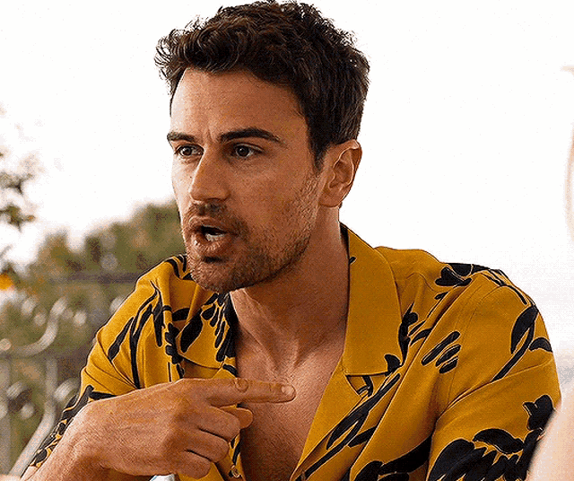 a man with a beard wearing a yellow shirt is pointing at something .