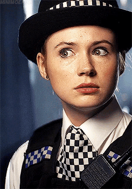 a woman wearing a hat and tie has a walkie talkie in her pocket