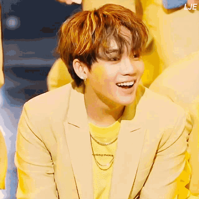 a young man wearing a yellow jacket and a yellow t-shirt that says gro paris smiles