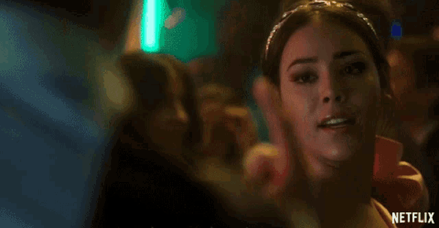 a woman wearing a headband and a red dress is smiling and giving a middle finger .