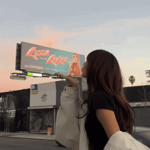 a woman stands in front of a billboard that says alterego