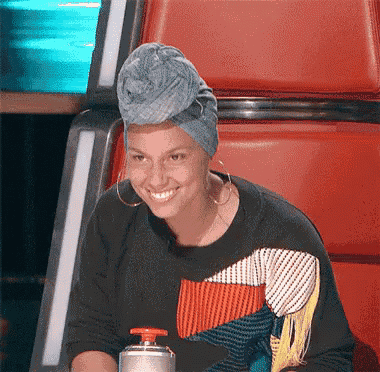 a woman wearing a turban and earrings smiles while sitting in a chair