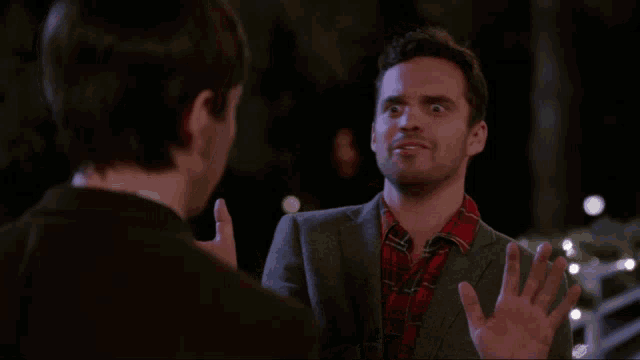 a man in a suit and plaid shirt talks to another man and says shuut up