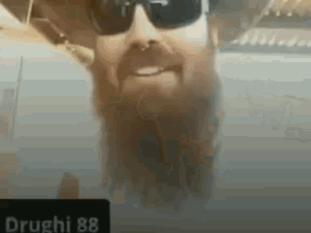 a man with a beard wearing sunglasses is smiling .